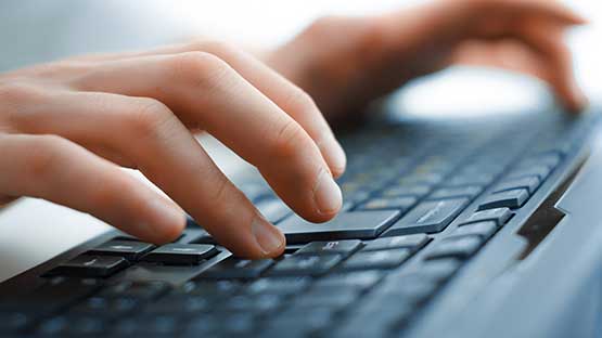 Hands typing on a computer keyboard