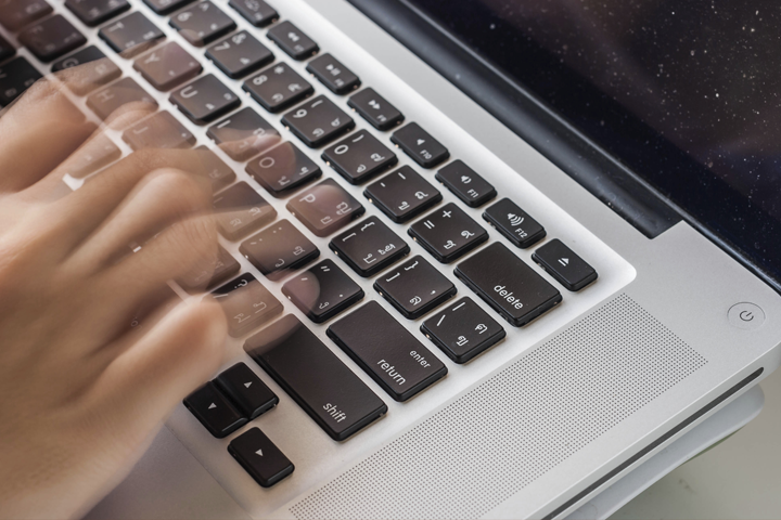 blurred image of hands typing fast on a keyboard